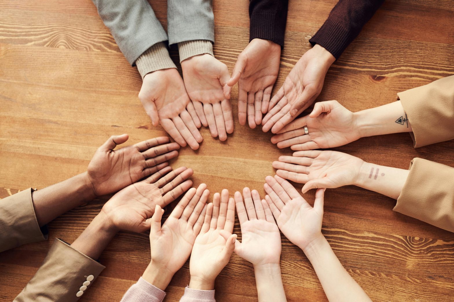 Multiple hands palms-up in a circle from people of different races.